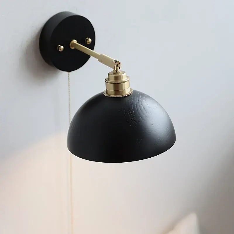 Industrial black and brass wall light fixture with matte wooden sconce and adjustable arm for bedroom use