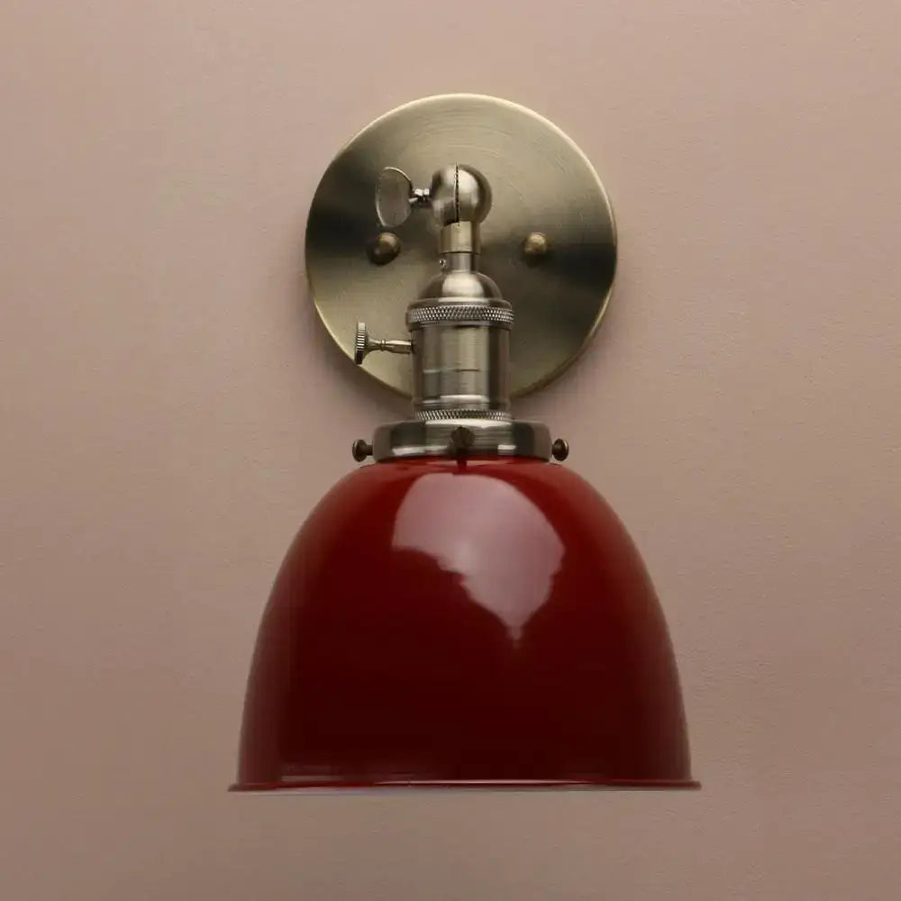 Industrial black wall sconce with adjustable arm featuring a vintage red enamel shade and brushed nickel hardware for bedroom