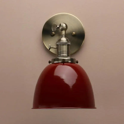 Industrial black wall sconce with adjustable arm featuring a vintage red enamel shade and brushed nickel hardware for bedroom
