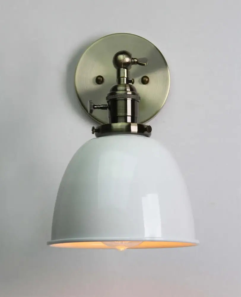 White enamel dome wall sconce with brushed brass mounting plate paired with industrial black wall sconce features