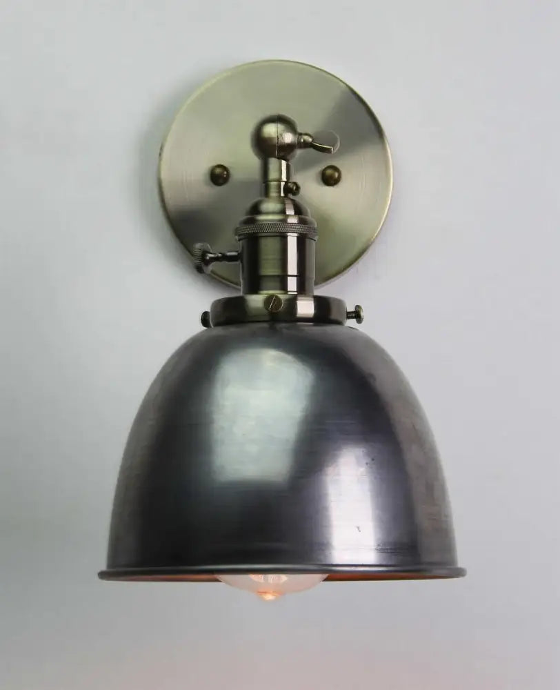 Industrial black wall sconce with matte black metal dome shade and brushed brass hardware for adjustable bedroom use