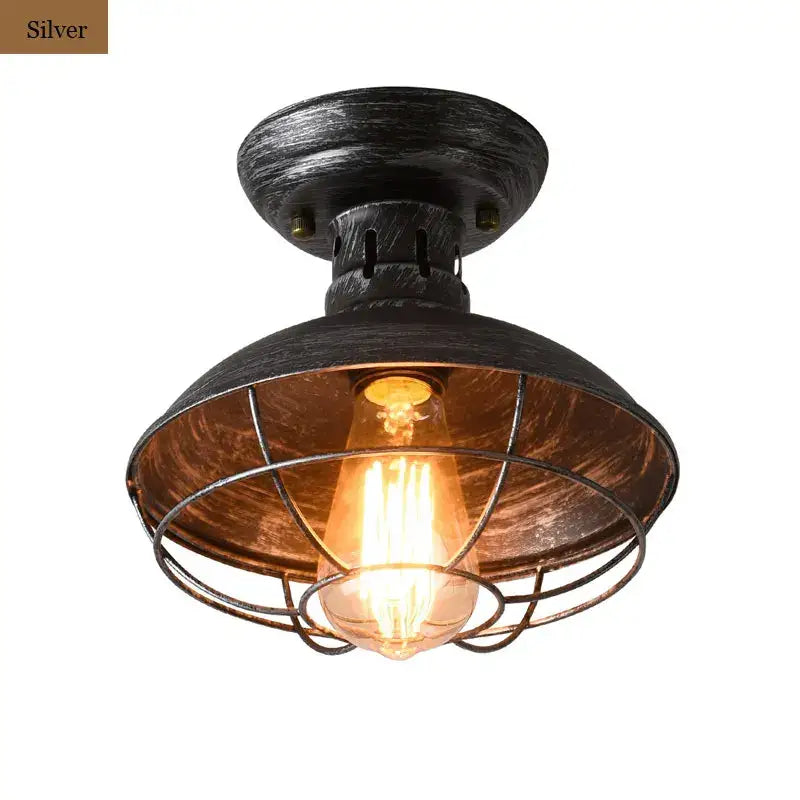 Silver industrial ceiling light with distressed metal finish and black cage housing glowing filament bulb decorbites industrial ceiling