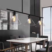 Black industrial-style pendant island lamp with three cone clear glass shades and exposed filament bulbs for dining table