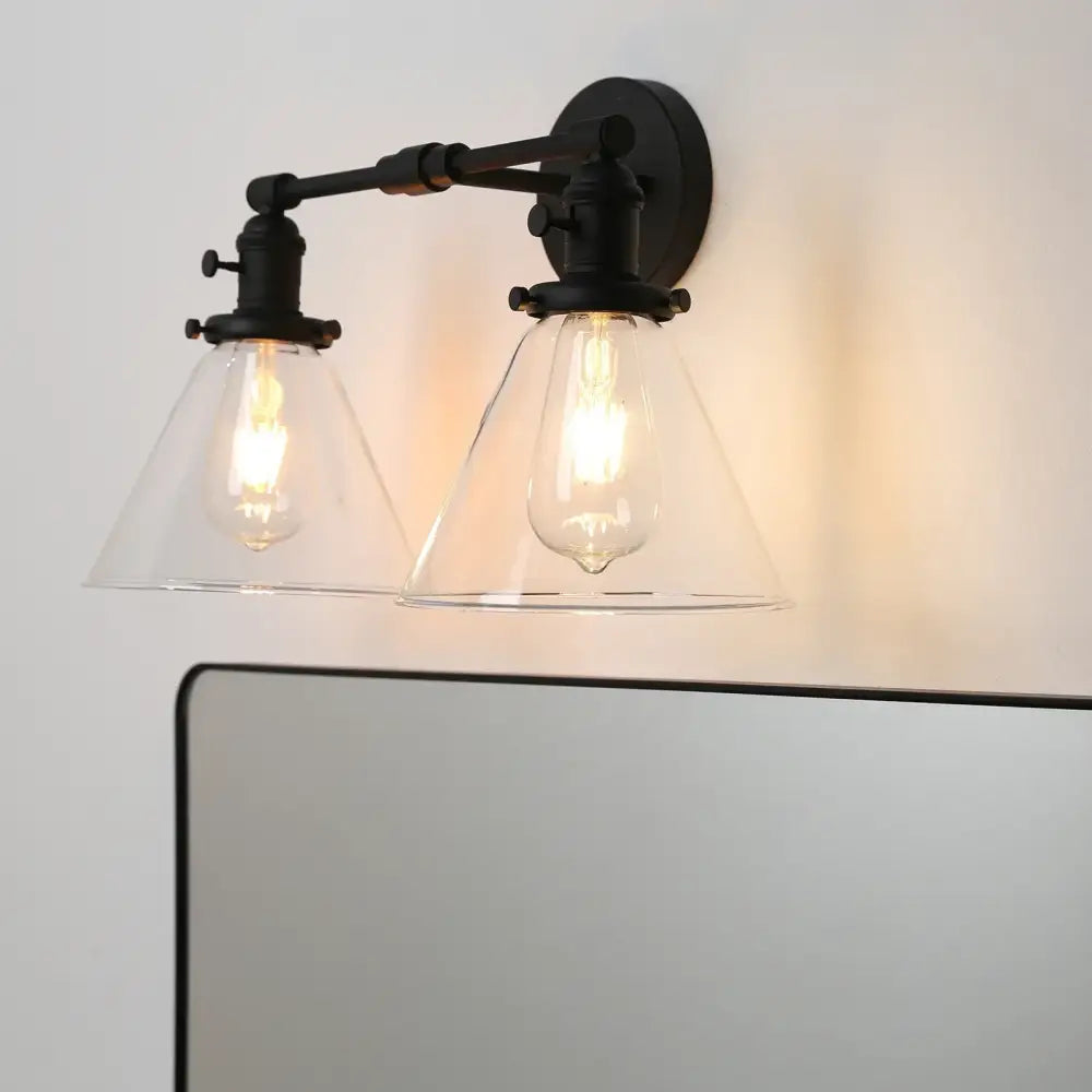 Black wrought iron wall sconce with double cone glass shades and exposed filament bulbs for industrial bedroom lighting