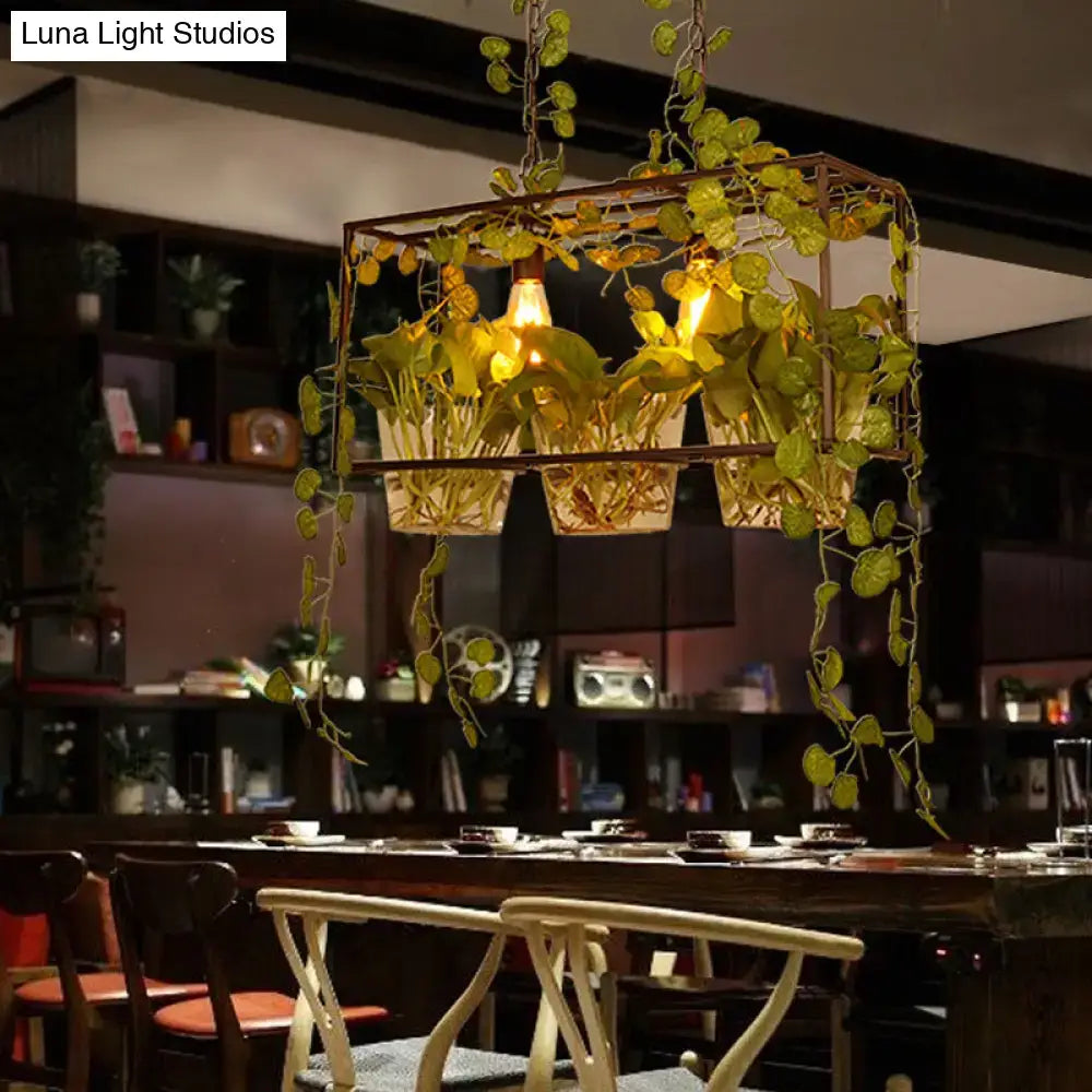 A rustic black metal industrial plant pendant light with lush green vines and adjustable chain cord length for dining rooms