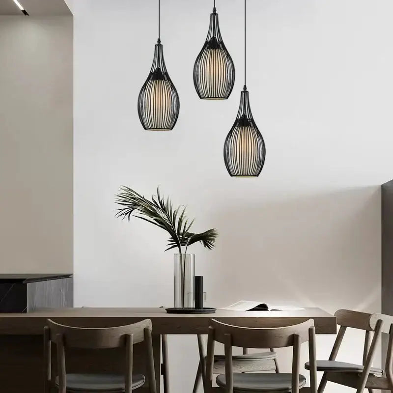 Three black iron cage pendant lights with modern teardrop design hang above dining table decorbites iron cage