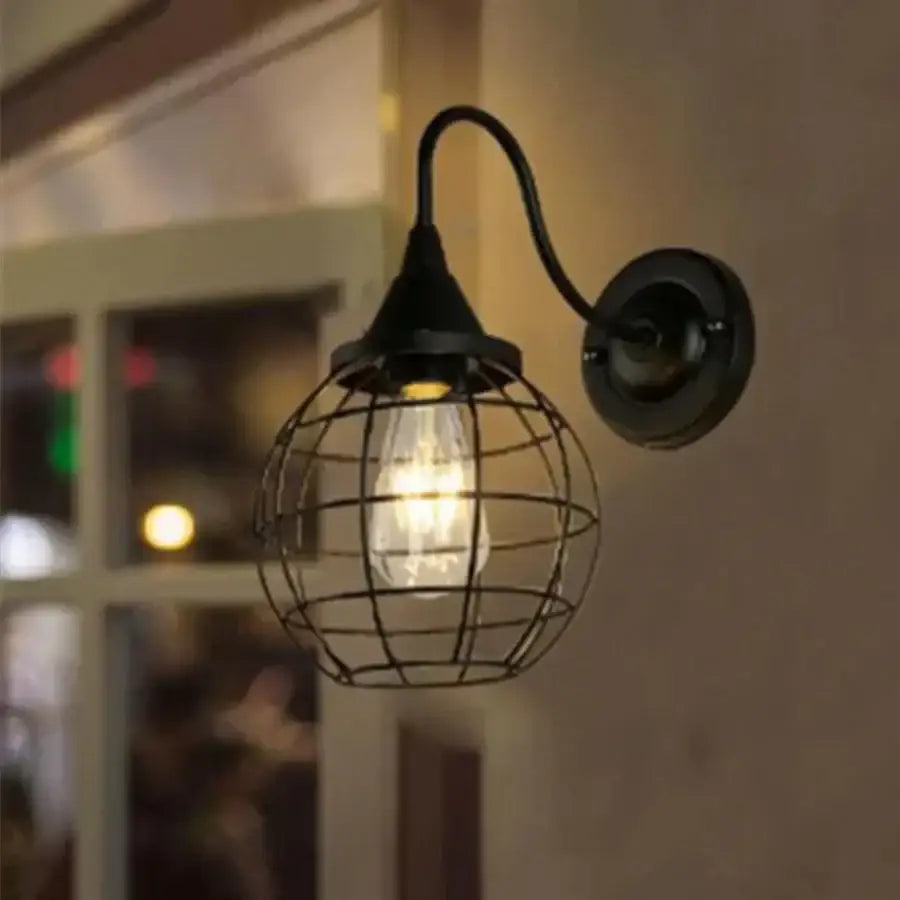 Black wrought iron cage wall sconce with spherical cage and exposed Edison bulb for bedroom decorbites iron cage lighting