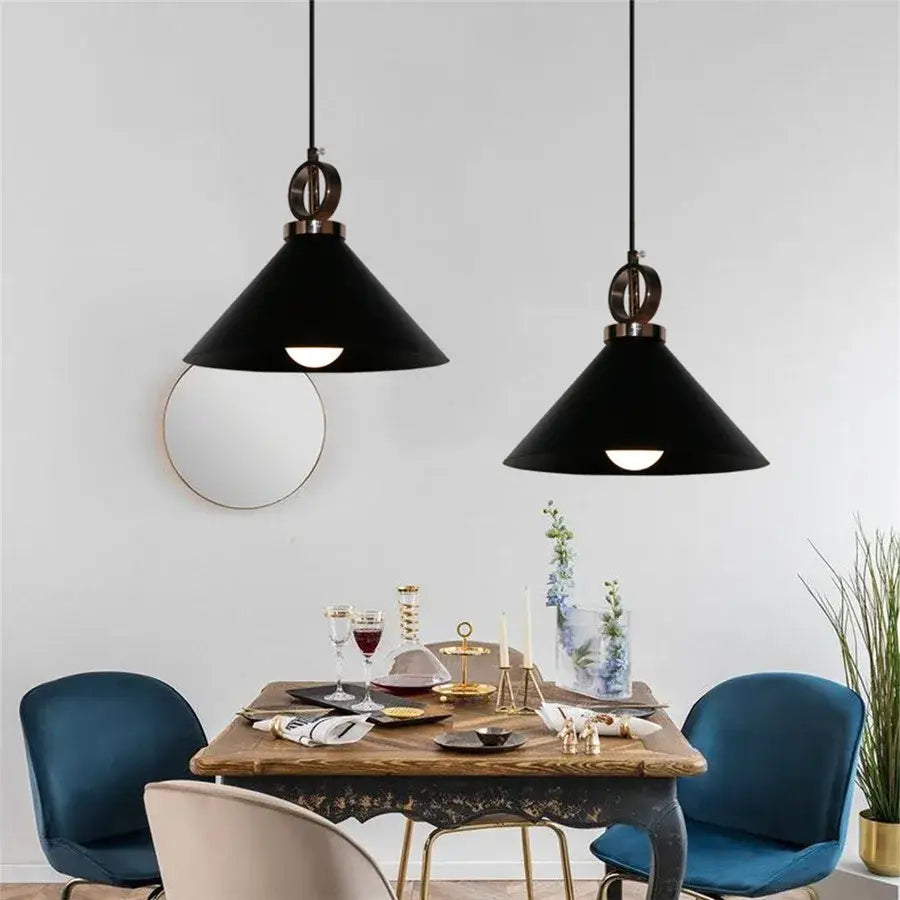 Black conical industrial iron pendant lights with brass accents hanging above a dining table decorbites industrial iron pendant