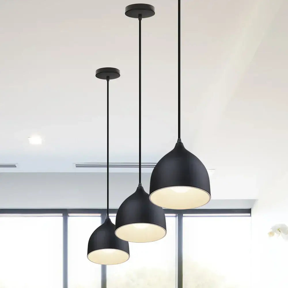 Set of three black matte industrial aluminium pendant lights with dome shades and warm interior glow for kitchen decorbites