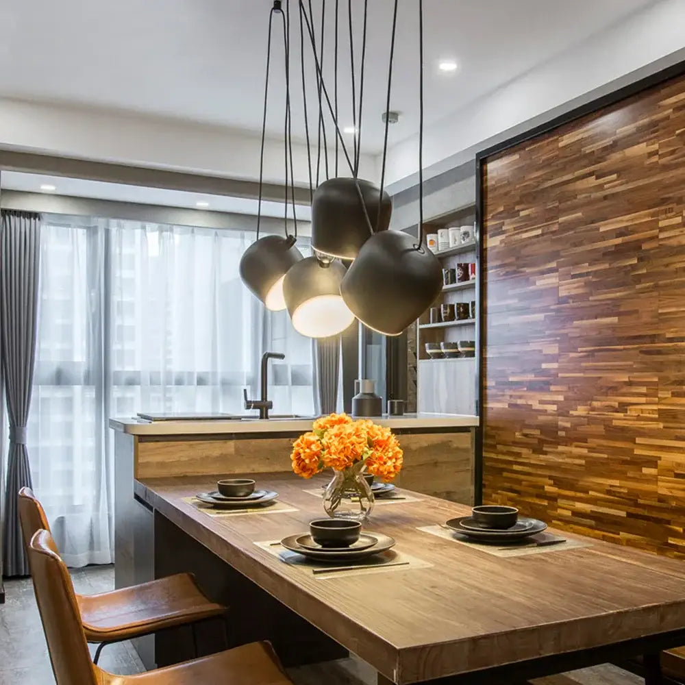 Modern black matte decorbites industrial spider pendant lamp with rounded overlapping shades above wooden dining table
