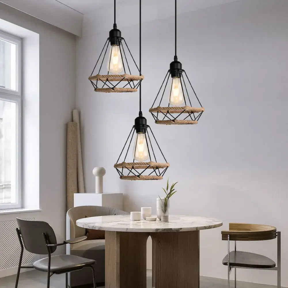 Three black metal decorbites industrial hanging lamps with woven rope and exposed bulbs over marble table