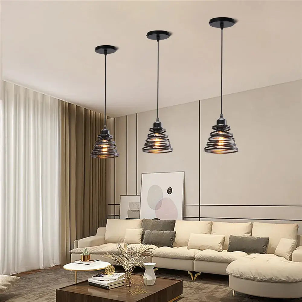 Three black industrial metal cage mini pendant lights with spiral shades hang from ceiling in dining room setting