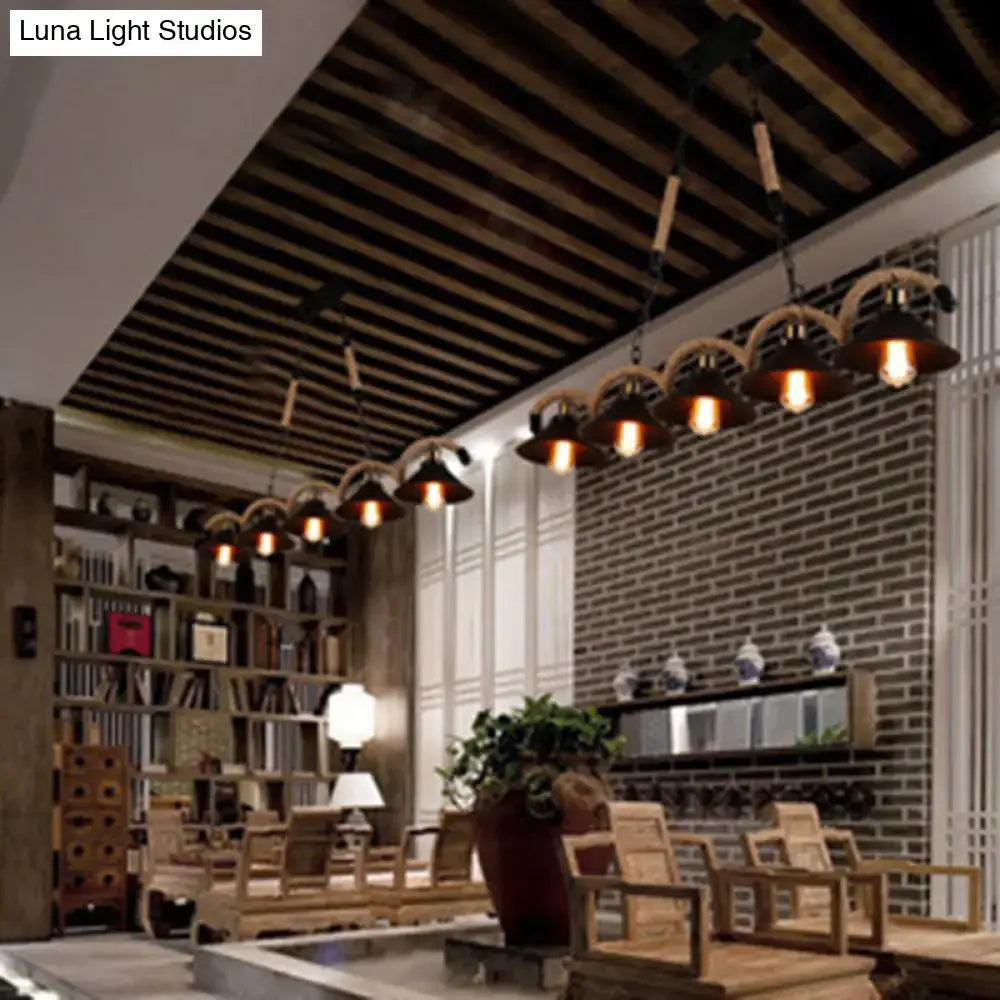 Industrial black metal island chandelier with dark metal shades and woven rope accents hanging from wooden ceiling