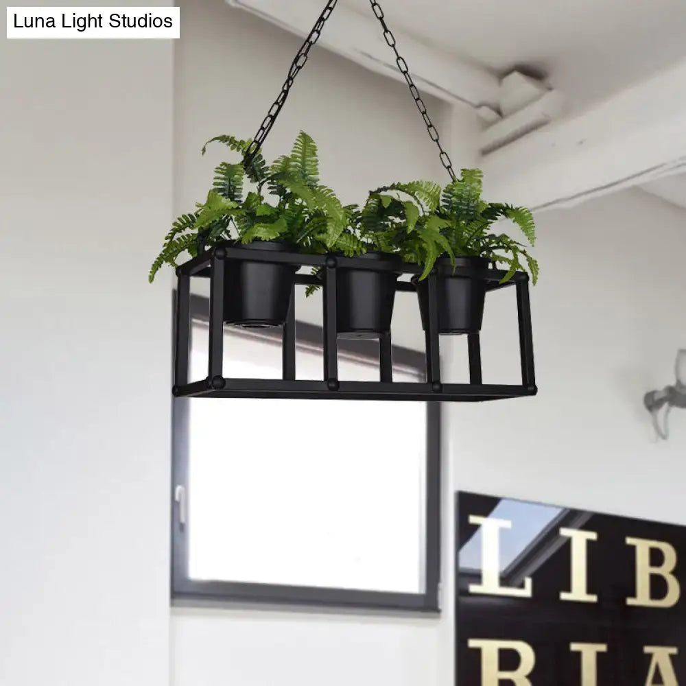 Black metal hanging planter with three small pots holding green ferns paired with industrial rectangle island light fixture