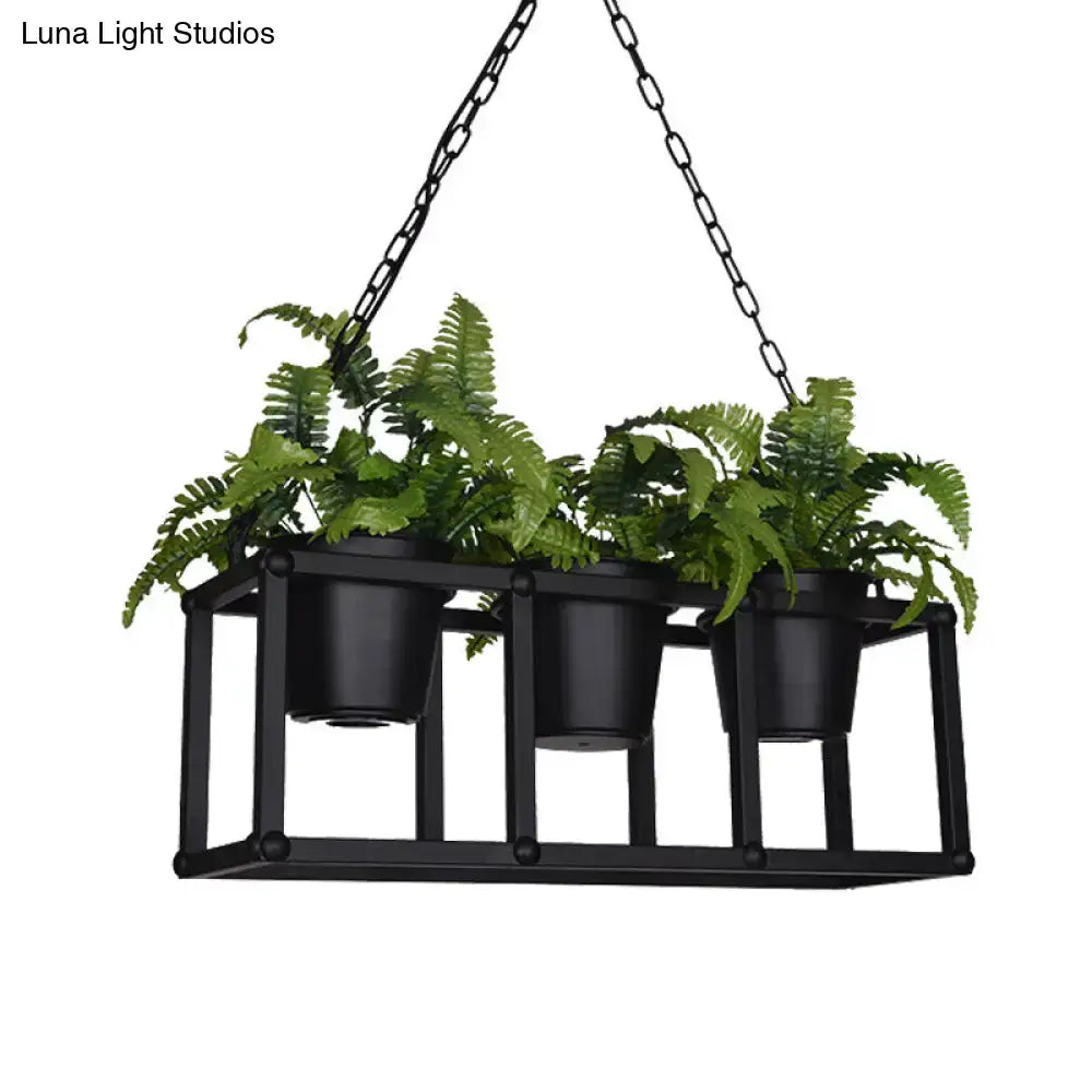 Black metal industrial rectangle island light fixture with three hanging black pots holding lush green ferns