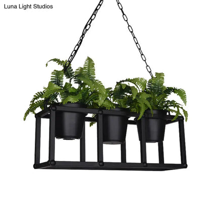 Black metal industrial rectangle island light fixture with three hanging black pots holding lush green ferns