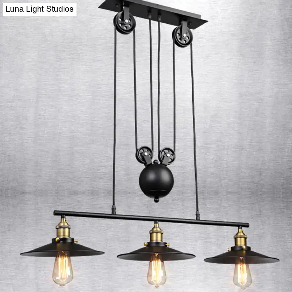 Industrial black metal pulley pendant light with three exposed edison bulbs and brass accents for kitchen island lighting