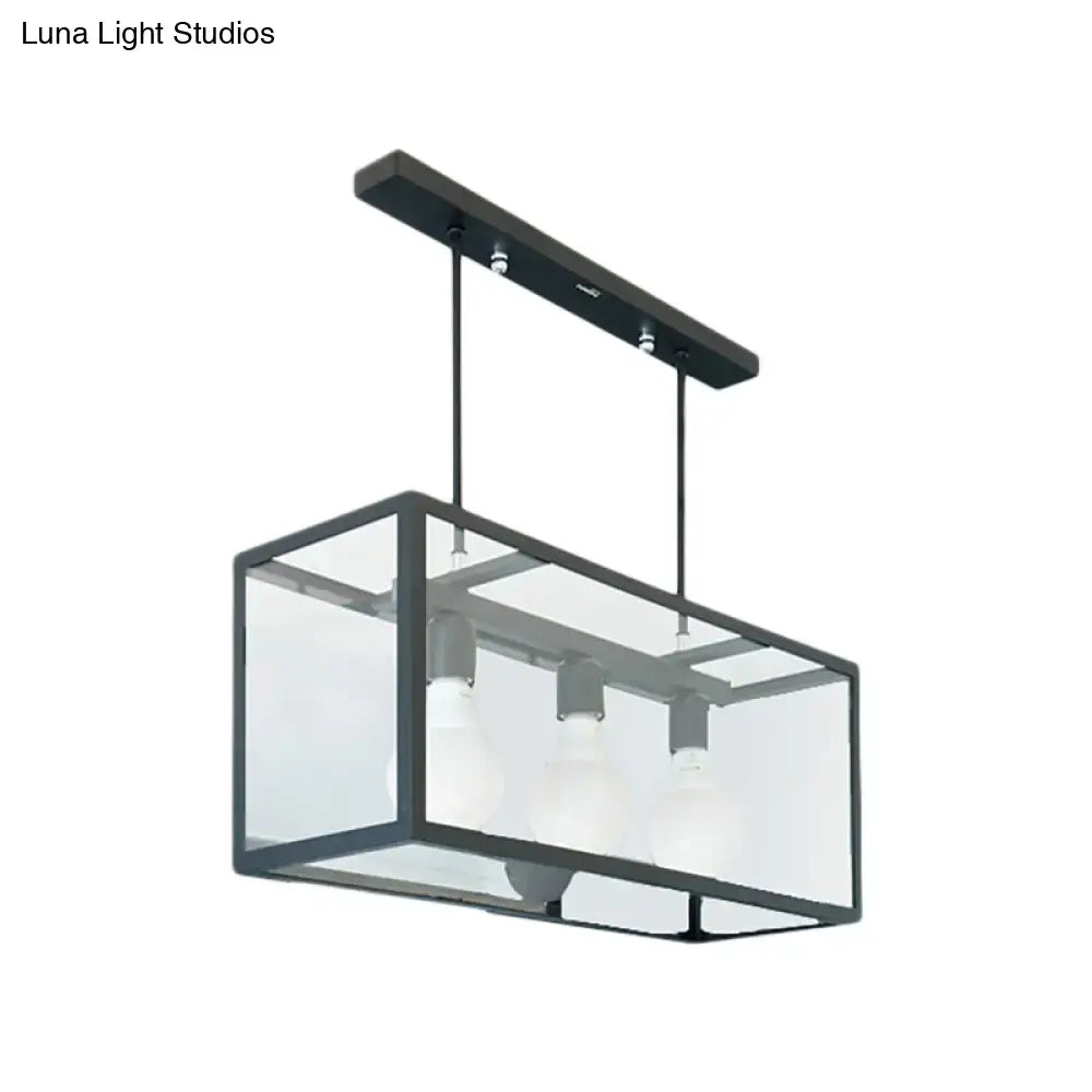 Black metal rectangular pendant light with clear glass panels and three exposed bulbs for industrial kitchen island use