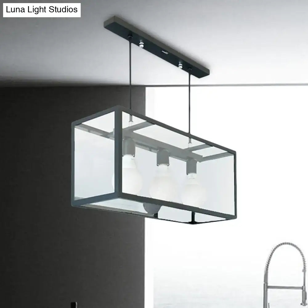 Modern rectangular pendant light with black metal frame and clear glass panels for industrial kitchen island use