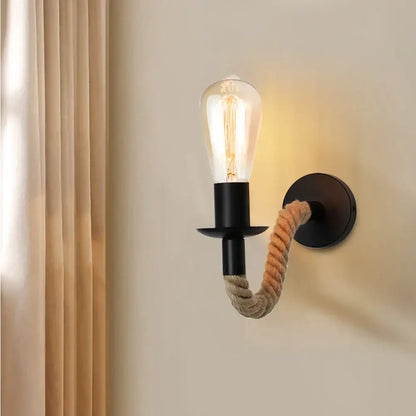 Industrial black metal wall lamp with coiled beige decorbites hemp rope arm and exposed filament bulb for bedroom decor