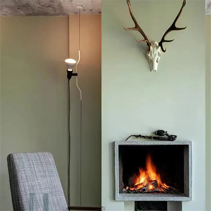 A modern industrial black wrought iron adjustable pendant lamp with exposed bulb and sleek white cord for bedroom decor