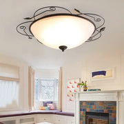Industrial black wrought iron round ceiling light with ornate leaf design and frosted glass dome for bedroom use