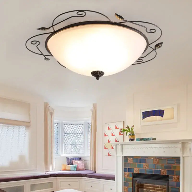 Industrial black wrought iron round ceiling light with ornate leaf design and frosted glass dome for bedroom use