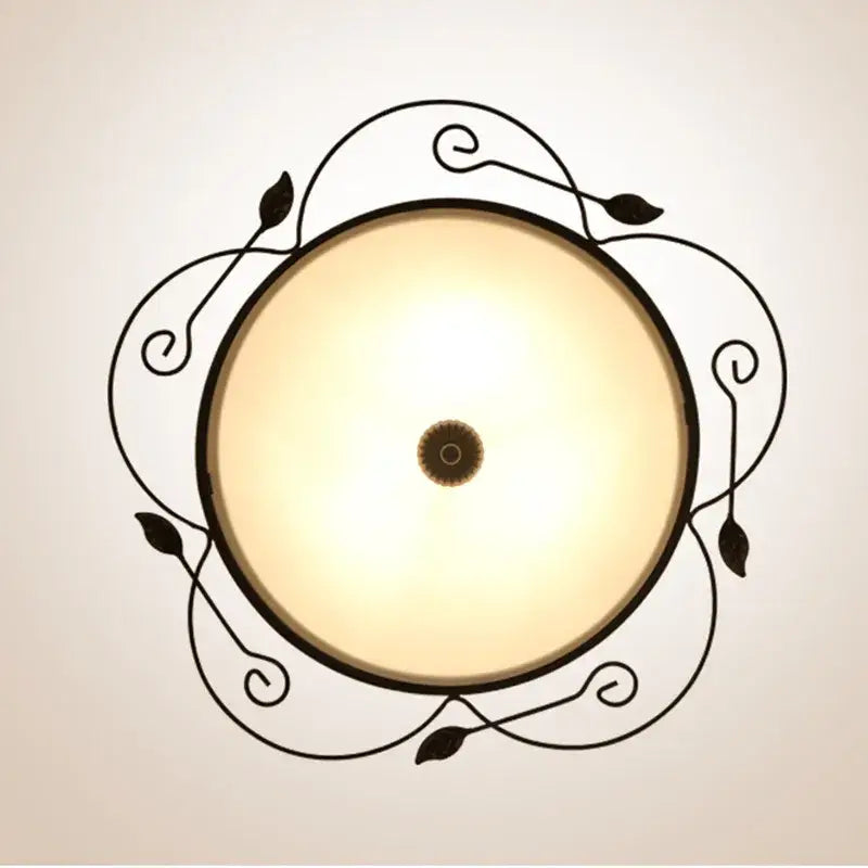 Industrial black wrought iron round ceiling light with ornate leaf designs and warm glass round ceiling shade