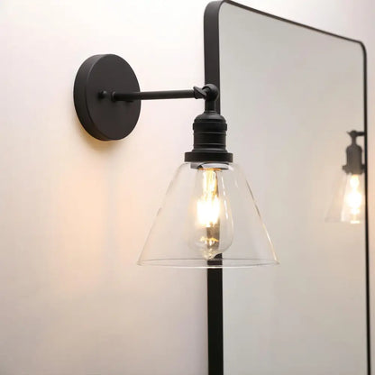 Industrial black wrought iron wall lamp with clear glass shade and exposed edison bulb for bedroom use