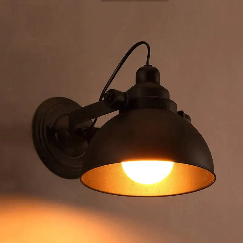 Industrial black wrought iron wall sconce with matte metal shade emitting warm amber light by decorbites industrial black wall lamp
