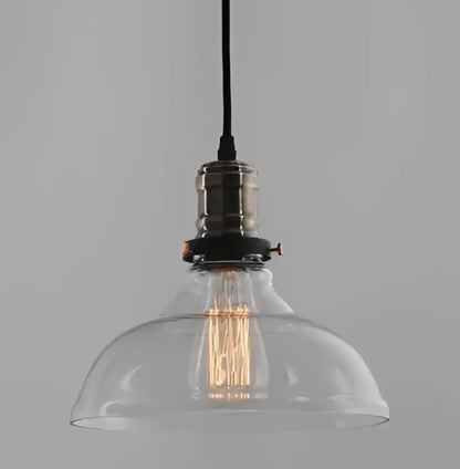 Clear glass pendant light with vintage edison bulb and brass-finished metal fixture for dining room use