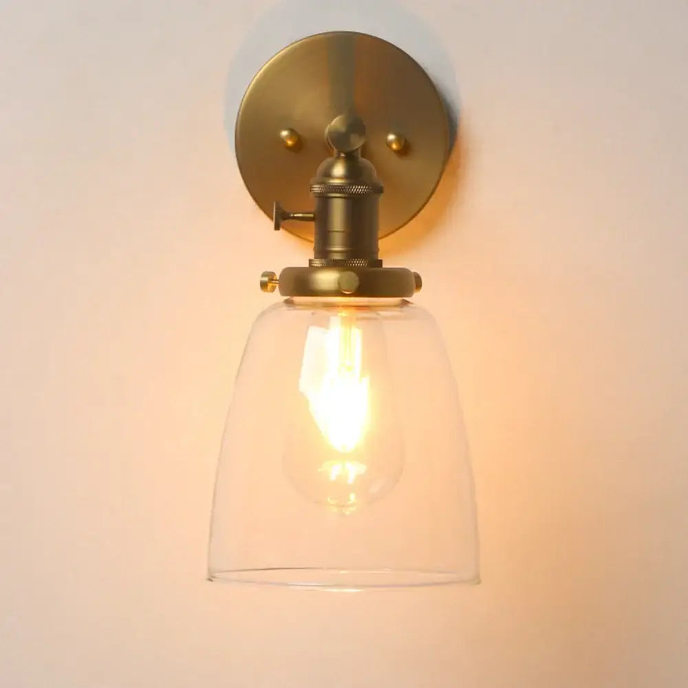 Antique brass wall sconce light with clear glass shade and exposed filament bulb for industrial bedroom use