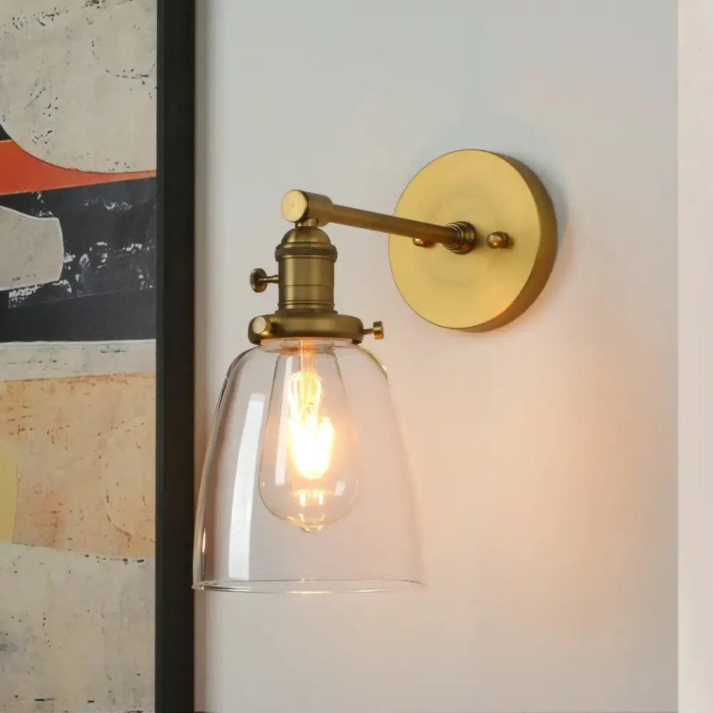 Industrial brass glass wall sconce light with clear bell-shaped shade and exposed filament bulb for bedroom use