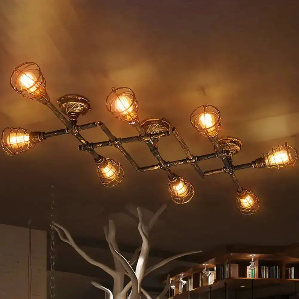Industrial brass intersecting piping ceiling light with six warm bulbs in wire cages on a dark metal frame