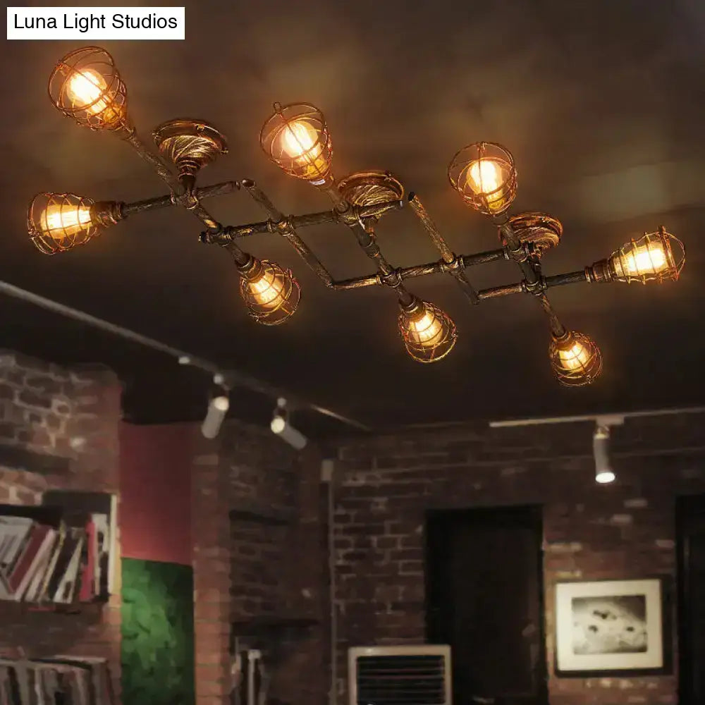 Industrial brass intersecting piping ceiling light with warm bulbs in wire cages on dark metal frame for dining room