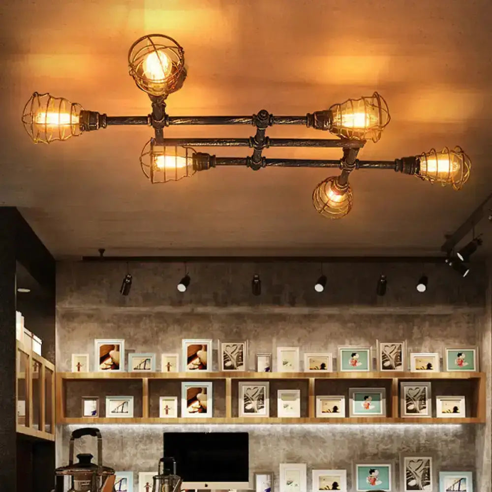 Industrial brass intersecting piping ceiling light with four exposed bulbs encased in wire mesh cages for dining room