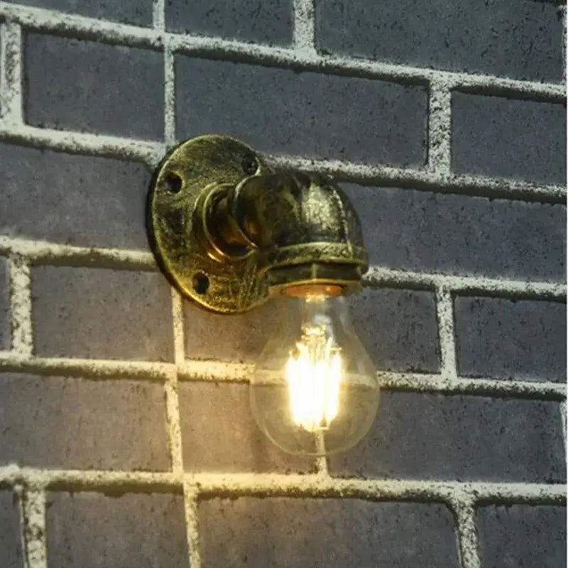 Industrial brass pipe wall sconce with glowing filament bulb featuring decorbites industrial iron pipe design for bedroom use
