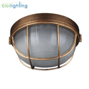 Antique brass-finished industrial-style outdoor ceiling lamp with frosted glass dome and bronze metal cage for yard lighting