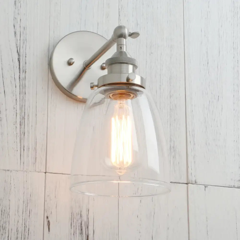A sleek industrial brushed nickel wall lamp with clear glass dome and exposed filament bulb decorbites clear glass design