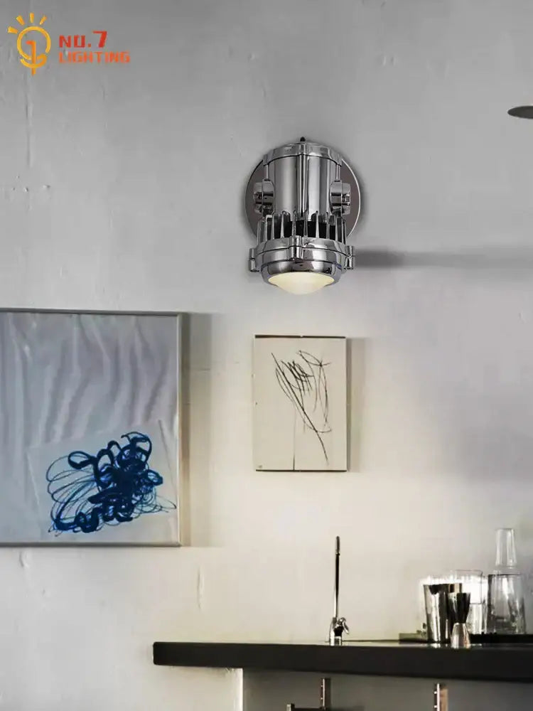 Industrial chrome adjustable wall lamp featuring a cylindrical segmented design and exposed bulb for bedroom lighting