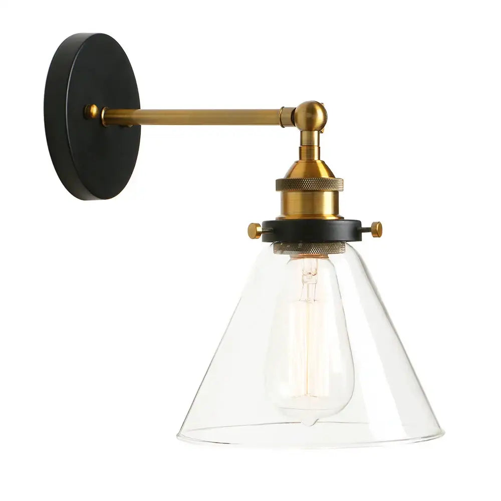 A sleek brass and black wall sconce with a clear glass shade and exposed filament bulb light fixture for bedrooms