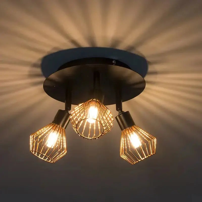 Black ceiling-mounted industrial copper diamond cage chandelier with three golden wire bulbs emitting warm glow