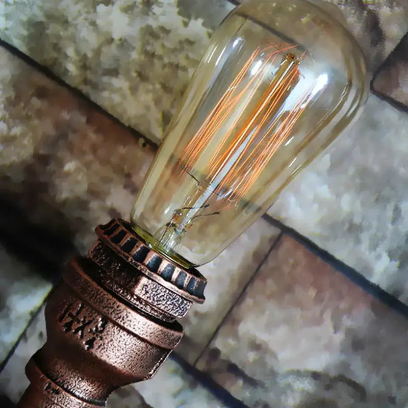 Vintage-style edison bulb with copper filament in amber glass on ornate bronze base industrial iron pipe wall sconce decorbites