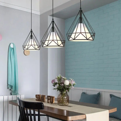 Three black geometric diamond cage pendant lights with white glass shades hang above a dining table for kitchen and living room