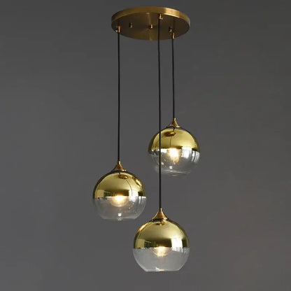 Modern brass finished industrial glass pendant light with three reflective gold and transparent glass spheres for dining room