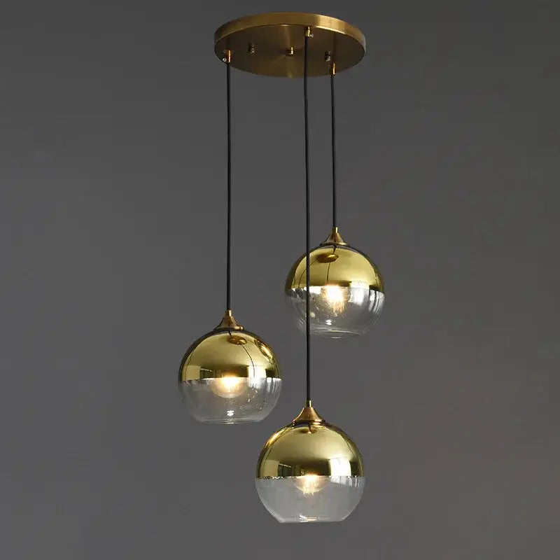 Modern brass finished industrial glass pendant light with three reflective gold and transparent glass spheres for dining room
