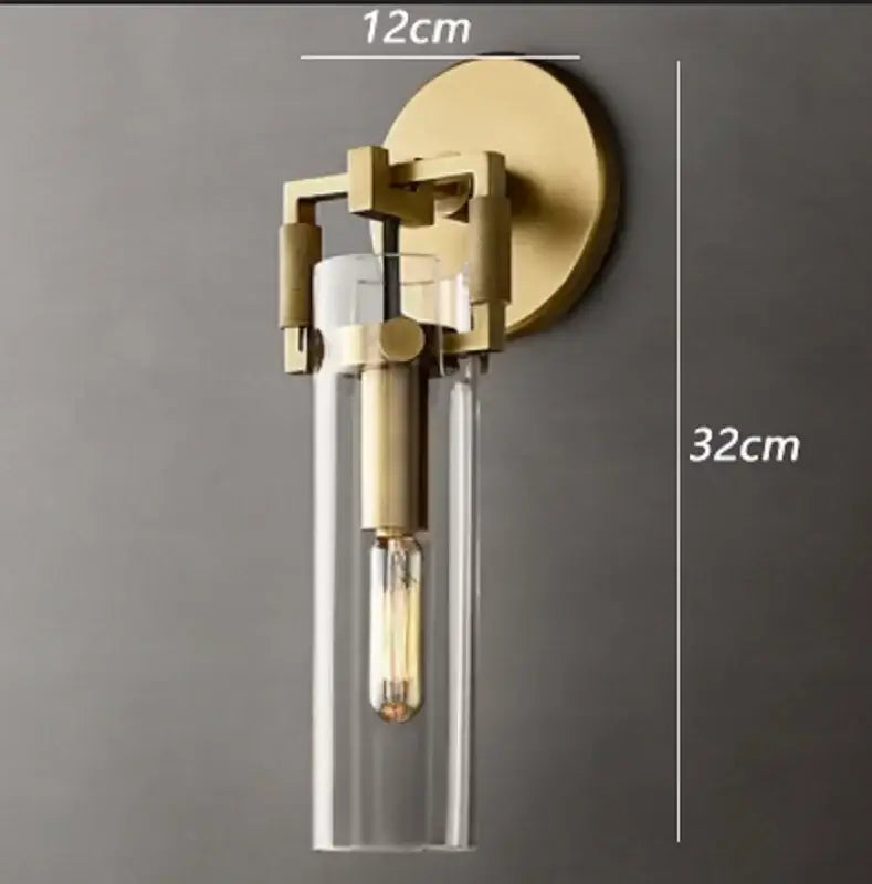 A modern brass-finished wall lamp with clear glass cylinder and exposed filament bulb for decorbites industrial glass wall decor