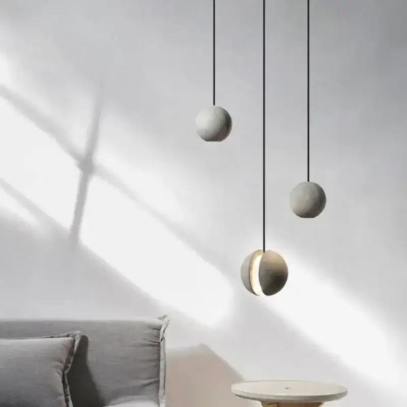 Three industrial gray and gold decorbites cement pendant light spheres hang with one illuminated for dining room decor