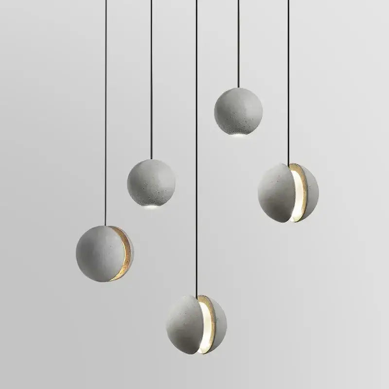 Industrial gray and gold decorbites cement pendant light with sphere shape and gold-accented cutouts for dining room decor