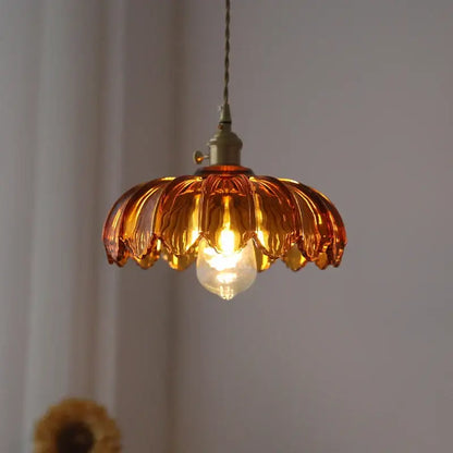 Amber-colored petal glass pendant light with brass hardware in a decorbites glass industrial style for dining room use